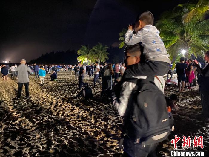 一位儿童坐着父亲的肩上用望远镜观看文昌航天发射场。凌楠 摄