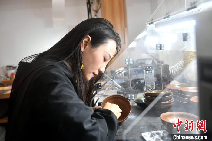 在唐洁工坊内，“90后”文物修复师瞿汕正低头忙碌。　吕明 摄